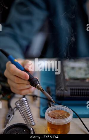 Ein professioneller Techniker stellt den Laptop mit verschiedenen Spezialwerkzeugen wieder her. Elektronische Reparaturwerkstatt, Technologiesanierung, Geschäft, Konzeptreparaturen. Mann, der Teile eines zerlegten Laptops repariert Stockfoto