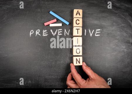 Vorbeugende Maßnahmen. Kreuzworträtsel aus Holzblock und Kreideflächen auf einem Tafel-Hintergrund. Stockfoto