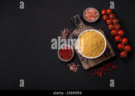 Rohe Aellini-Nudeln aus Hartweizen mit Salz und Gewürzen auf dunklem Betonhintergrund Stockfoto