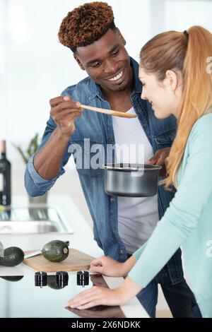 Er bietet seiner Freundin Essen auf Holzlöffel an Stockfoto