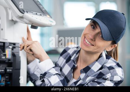 Glückliche Frau, die einen Drucker repariert Stockfoto