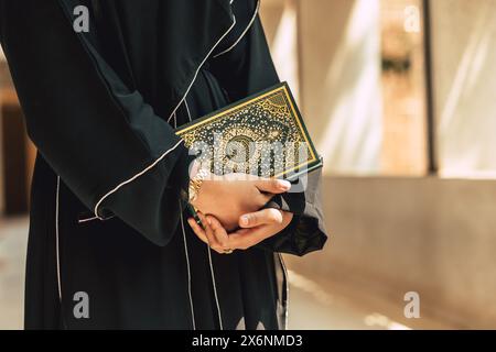 Heiliger Koranbucheinband mit arabischer Kalligraphie übersetzen die Bedeutung des Al-Koran. Die Hand der Araber hält ein muslimisches Koran-Buch. Stockfoto