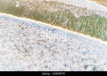 Aus der Vogelperspektive mit Drohne auf die schäumenden Wellen am Ufer eines Strandes bei Ebbe. Bild-Konzept für den Sommer Stockfoto