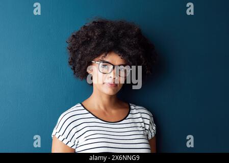 Schwarze Frau, Porträt und Serious mit Brille für Optometrie oder Sehen und auf blauem Studiohintergrund. Mädchen, Brille und selbstbewusst für Wellness, Auge Stockfoto