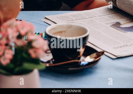 Eine Tasse Kaffee und eine Zeitung auf einem Tisch im Restaurant, ohne sich auf den Zweck zu konzentrieren Stockfoto