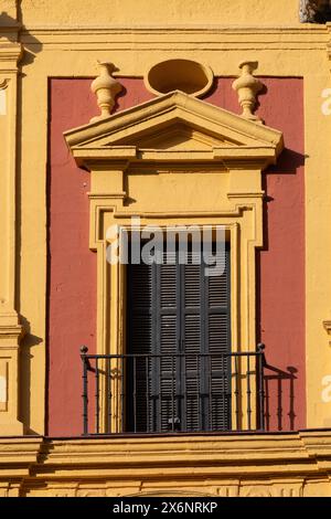 Rot-gelb lackiertes Gebäude, Tür und Balkon in einem klassischen spanischen Gebäude in Malaga, Andalusien, Südspanien. Stockfoto