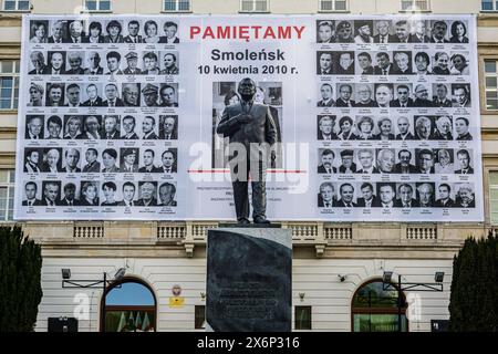 Eine Statue von Lech Kaczy?Ski steht vor einem Banner mit Porträts aller 96 Passagiere, die bei der Luftkatastrophe ums Leben kamen. Polen erinnert an den 14. Jahrestag der Flugunglücke in Smole?SK, bei der der polnische Präsident Lech Kaczy?Ski, seine Frau Maria und 94 weitere Würdenträger und Crew ums Leben kamen. Angesichts der Gegenpathie zwischen der Partei Recht und Gerechtigkeit, die von Kaczy?Skis Zwillingsbruder Jaros?aw geführt wird, und der Bürgerkoalition unter der Leitung des aktuellen polnischen Premierministers Donald Tusk, wird der Jahrestag nun von den Konservativen und der religiösen Rechten des Landes öffentlich begangen. Stockfoto