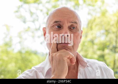 Kluger charismatischer Mann, älter als 65 Jahre, der über das Leben nachdenkt, verloren im Denken, altersbedingte Veränderungen, was tief in Gedanken suggeriert Stockfoto