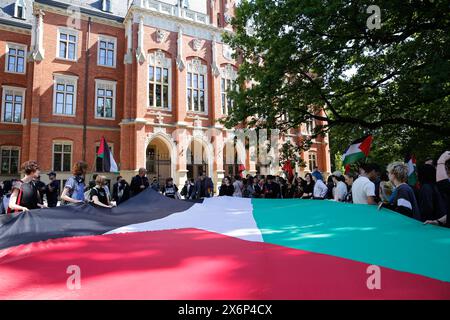 Studenten singen pro-palästinensische Parolen und halten palästinensische Fahnen und Banner während der ersten Demonstration in Polen, die von Studenten und Gelehrten gegen den israelischen Angriff auf den Gazastreifen vor dem Collegium Novum, dem Büro des Dekans der Jagiellonen-Universität in Krakau, Polen, am 15. Mai 2024 organisiert wurde. Stockfoto