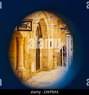 Jaffa, Israel - 10. Mai 2024: Blick durch ein Fenster einer typischen Gasse in der Altstadt von Jaffa, heute Teil von Tel-Aviv-Yafo, Israel Stockfoto