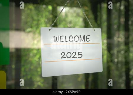 Willkommen 2025 auf einem Schild, hängt an einer Glastür. Stockfoto