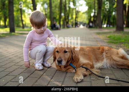 Kind mit Hund. Kinderschläge Labrador Retriever Hund auf Kopf im Park. Tierpflege. Stockfoto