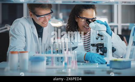 Modernes medizinisches Forschungslabor: Porträt von schwarzen und kaukasischen jungen Wissenschaftlern mit Mikroskop, Digital Tablet, Sample Analysis, Talking. Ein vielseitiges Team von Spezialisten arbeitet im Advanced Lab Stockfoto