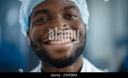 Nahaufnahme Porträt eines gutaussehenden Schwarzen Afroamerikaners in einem hellblauen Freizeitshirt. Erfolgreicher Mann lächelt ruhig, während er die Kamera ansieht. Glücklicher stilvoller Geschäftsmann oder Arzt im Krankenhaus. Stockfoto