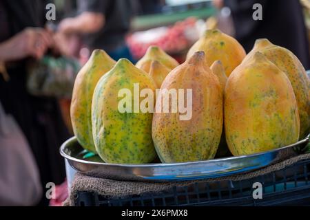 Die Nahaufnahme zeigt reife Papayas auf einem Tablett, die auf einem geschäftigen Basar oder einem lebhaften Obstladen zum Verkauf angeboten werden Stockfoto