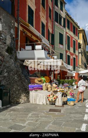 Stand mit Hüten und Strohsäcken am Pier des kleinen Hafens des alten Fischerdorfes im Sommer, Portofino, Genua, Ligurien, Italien Stockfoto