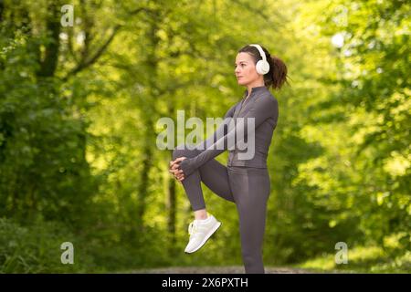 Frau, die Beindehnungsübungen macht, bevor sie im Park läuft und joggt Stockfoto