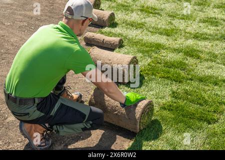 Der Gärtner legt vorsichtig Gras auf einem Rasen ab. Installation Von Grasrasen. Stockfoto