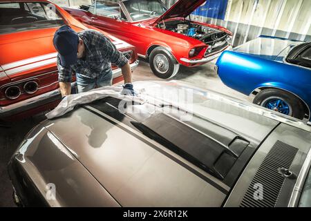 Ein Mann wäscht die Motorhaube eines Oldtimers in der Garage. Klassische Fahrzeuge Stockfoto