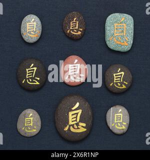 Chinesisches Zeichen xi oder japanisches Iki, was Ruhe bedeutet, geschrieben auf Kieselstein Stockfoto
