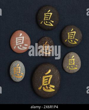 Chinesisches Zeichen xi oder japanisches Iki, was Ruhe bedeutet, geschrieben auf Kieselstein Stockfoto