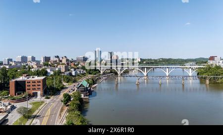 Ein Blick aus der Vogelperspektive von Knoxville, Tennessee, zeigt ein pulsierendes Stadtbild mit einer Mischung aus historischen und modernen Gebäuden, dem Tennessee River, der sich durch die Innenstadt schlängelt, üppigen grünen Parks und den fernen Smoky Mountains, die den Horizont säumen. Stockfoto