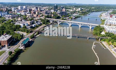 Ein Blick aus der Vogelperspektive von Knoxville, Tennessee, zeigt ein pulsierendes Stadtbild mit einer Mischung aus historischen und modernen Gebäuden, dem Tennessee River, der sich durch die Innenstadt schlängelt, üppigen grünen Parks und den fernen Smoky Mountains, die den Horizont säumen. Stockfoto