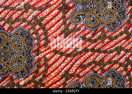 Draufsicht auf rot-gelben ankara-Stoff, flaches nigerianisches Wachstuch mit Motiven, ausgebreitetes rot-gelbes ankara-Material Stockfoto