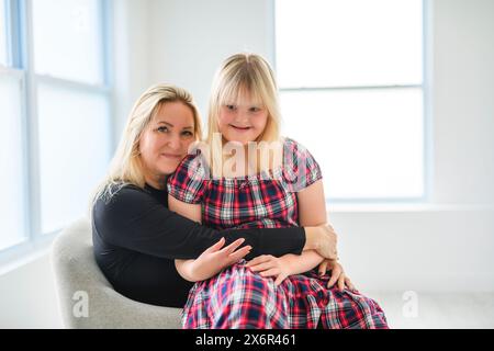 Mutter und Sweet Down Syndrom Tochter Mädchen auf dem Sofa zu Hause Stockfoto