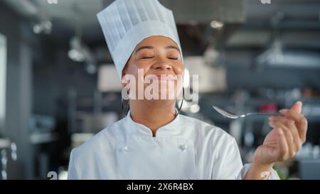 Restaurant Küche: Porträt der schwarzen Chefkoch, die Gerichte zubereitet, Essen verkostet und es genießt. Professionelles Kochen köstliches, authentisches, traditionelles Essen, mit gesunden Zutaten für Mahlzeit Rezept Stockfoto