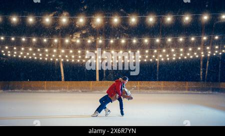 Winter Wonderland: Schlittschuhpaar, die Spaß an einem magischen Abend auf der Eisbahn haben. Wunderschöne Schneefälle, Lichter Leuchten. Boyfrined und Freundin in Liebe, Tanz, Umarmung, Eiskunstlauf. Weitsicht Stockfoto