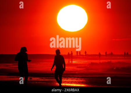 Isle Of Palms, Usa. Mai 2024. Menschen, die von einem dramatischen Sonnenaufgang umgeben sind, versammeln sich an einem klaren, heißen Tag am 16. Mai 2024 in Isle of Palms, South Carolina. Quelle: Richard Ellis/Richard Ellis/Alamy Live News Stockfoto