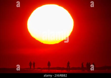 Isle Of Palms, Usa. Mai 2024. Menschen, die von einem dramatischen Sonnenaufgang umgeben sind, versammeln sich an einem klaren, heißen Tag am 16. Mai 2024 in Isle of Palms, South Carolina. Quelle: Richard Ellis/Richard Ellis/Alamy Live News Stockfoto