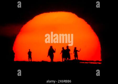 Isle Of Palms, Usa. Mai 2024. Super-Tele-Blick auf den dramatischen Sonnenaufgang mit Silhouetten, die Selfies machen, 16. Mai 2024 auf Isle of Palms, South Carolina. Quelle: Richard Ellis/Richard Ellis/Alamy Live News Stockfoto