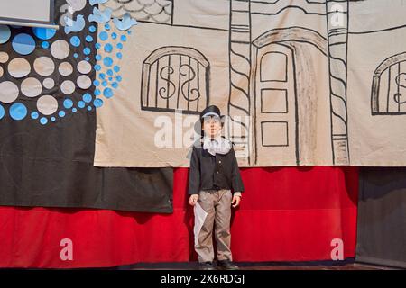 Porträt eines lateinischen Jungen bei einer Schulveranstaltung zum Unabhängigkeitstag in Argentinien mit einem Herrenkostüm und einer Hintergrunddekoration Stockfoto
