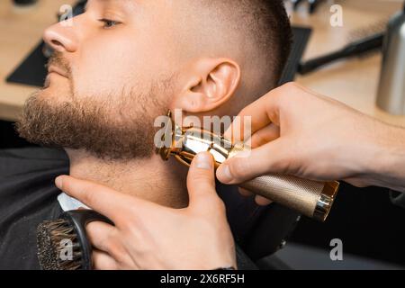 Der Friseur schneidet den Brünetten im Friseurladen die Haare Stockfoto