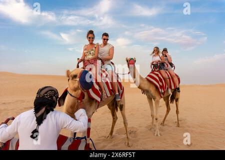 Dubai, VAE - 10.31.2018 : Kamelreiten in der Wüste mit zwei dekorierten Kamelen und Touristen Stockfoto