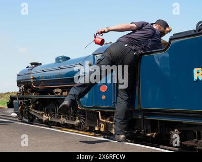 Ein Dampflokomotivfahrer, der die Samson-Lokomotive auf der Schmalspurbahn Romney, Hythe and Dymchurch Railway RH&DR in Dungeness Kent England, Großbritannien, betreut Stockfoto