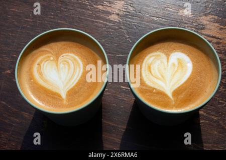 Zwei wiederverwendbare Tassen mit Cappuccino auf einem Holztisch in Nahaufnahme Stockfoto
