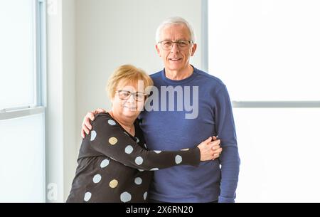 Fröhliches, träumliches, älteres Ehepaar der 60er Jahre, das sich vor Liebe umarmt Stockfoto