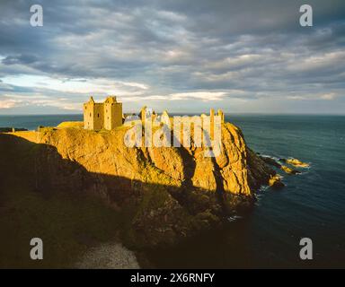 Die Ruinen des mittelalterlichen Dunnottar Castle in Aberdeenshire, Schottland, thronten hoch auf einem steilen Felsvorsprung hoch über der Nordsee, der bei Sonnenuntergang zu sehen ist. Stockfoto