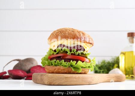 Köstlicher vegetarischer Burger und Zutaten auf weißem Holztisch Stockfoto