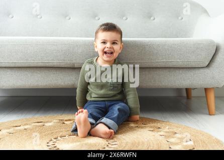 Der kleine 2-jährige sitzt zu Hause auf dem bequemen Sofa Stockfoto