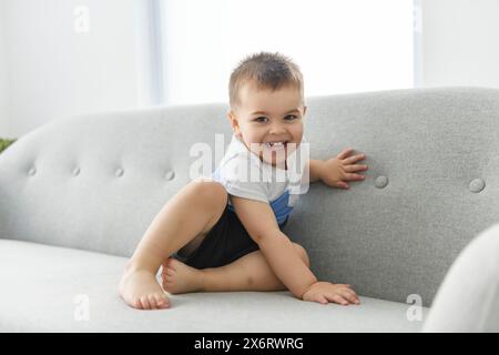 Der kleine 2-jährige sitzt zu Hause auf dem bequemen Sofa Stockfoto