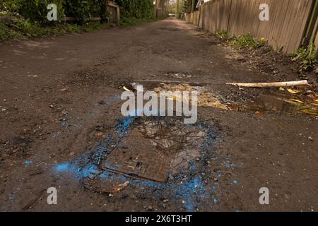 Blaue Sprühfarbe wurde erst 4 Wochen später zur Identifizierung eines Lecks im Leitungswasser verwendet, der die nicht genutzte Straße zerstörte Stockfoto