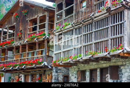 Balkone mit Blumen in den traditionellen alten Holzhäusern von Sappada Stockfoto