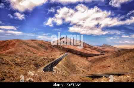 Einsame Straße durch das weite Land Fuerteventura, Vulkan, trocken, karg, Horizont, großer Himmel mit Wolken Stockfoto