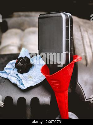 Motoröl durch einen Trichter in den Motor eines Fahrzeugs einfüllen Stockfoto