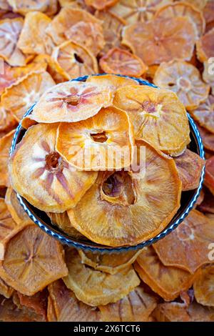 Getrocknete Persimmon-Scheiben aus organischem Anbau in einer dekorativen Schüssel, Nahaufnahme von getrockneten Persimmon-Scheiben aus organischem Anbau, die wunderschön in einer dekorativen Schüssel angeordnet sind. Stockfoto