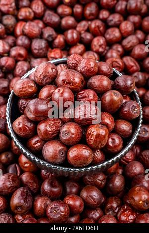 Frische Jujube-Früchte in einer Metallschale auf Stapelhintergrund, Nahaufnahme frischer Jujube-Früchte in einer Vintage-Metallschale, umgeben von einem Haufen Jujube-Früchte. Stockfoto